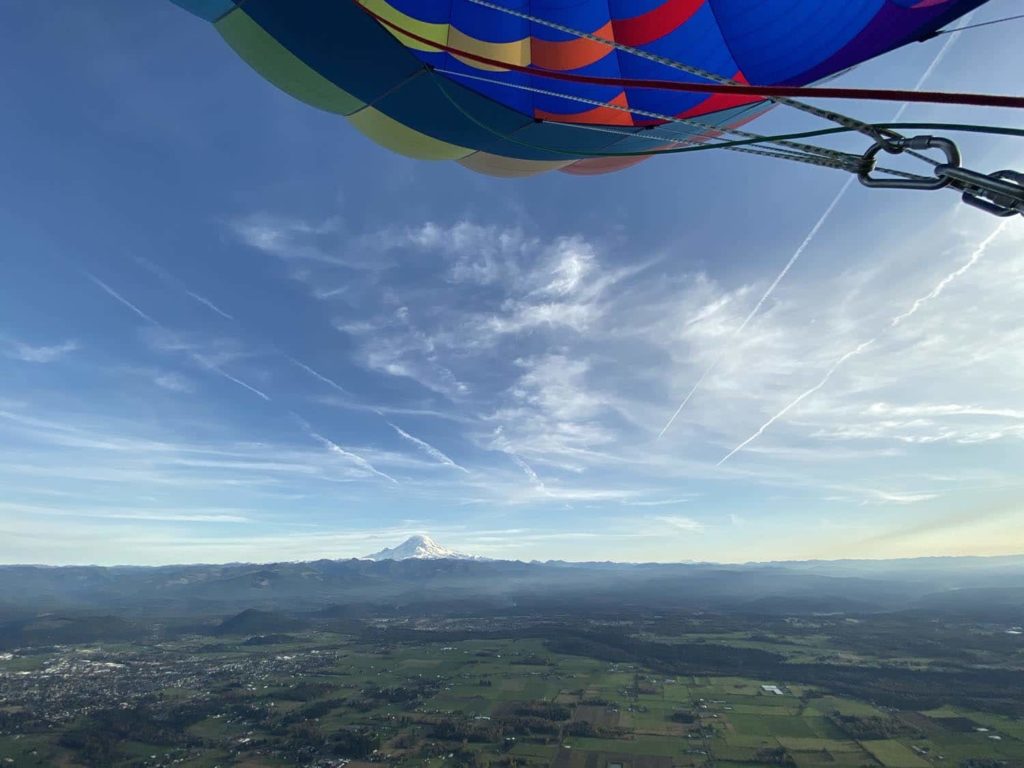Looking out at Mount Rainier at sunrise with stratus clouds and part of the hot air balloon envelope in view
