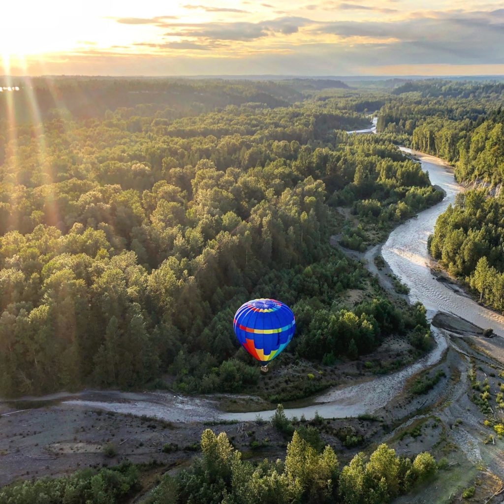 Hot air balloon with sun rays in the background flying South of Seattle