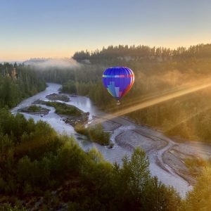Views of the Green River with a hot air balloon flying low over the water at sunrise