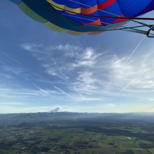 Looking out at Mount Rainier at sunrise with stratus clouds and part of the hot air balloon envelope in view