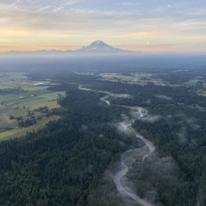 Hot air balloon flying over the White River. Beautiful view of the cascades and Mount Rainier