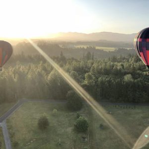 Two hot air balloons flying in front of Mount Rainier and the Cascade Mountains