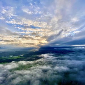 View from a hot air balloon with two layers of beautiful stratus clouds with the sun's rays popping through.