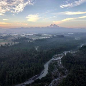 Pre-dawn view of Mt. Rainier and the White River from a hot air balloon. The sky is a combination of pastel colors, 10 minutes before sunrise
